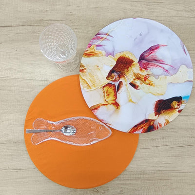 Mesa con bajoplato Funda Pez, mantel naranja, copa de cristal y bandeja de vidrio en forma de pez